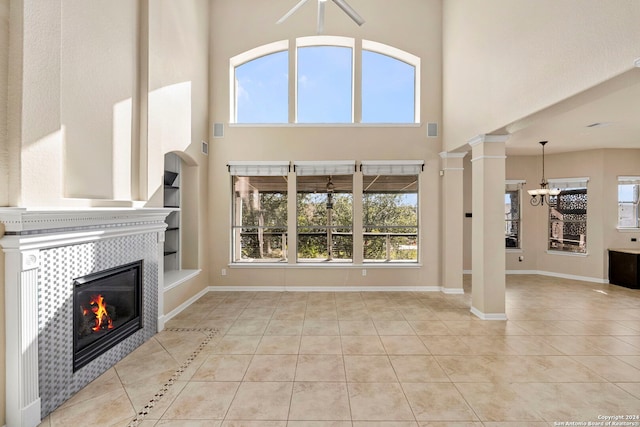 unfurnished living room with a tiled fireplace, light tile patterned floors, and ornate columns