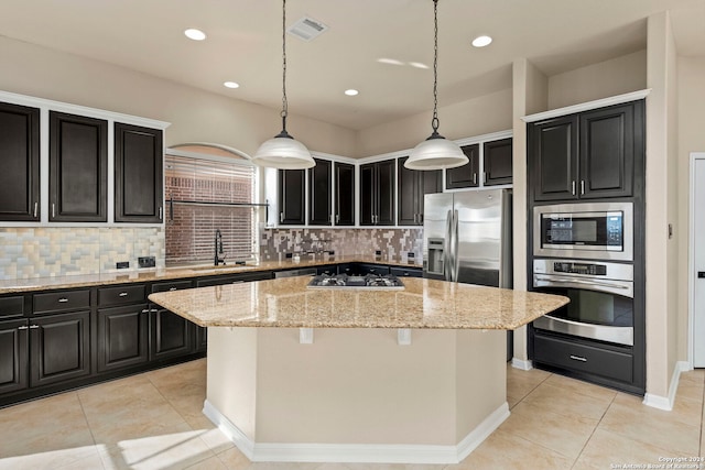 kitchen featuring decorative light fixtures, stainless steel appliances, a center island, and decorative backsplash