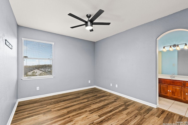 unfurnished bedroom featuring ceiling fan, connected bathroom, and light hardwood / wood-style flooring