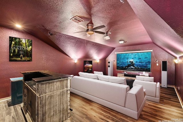 cinema with vaulted ceiling, ceiling fan, hardwood / wood-style floors, and a textured ceiling