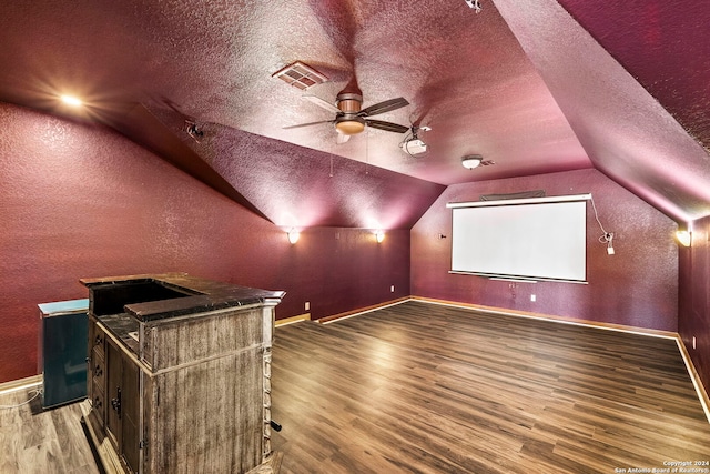 cinema featuring hardwood / wood-style flooring, ceiling fan, lofted ceiling, and a textured ceiling