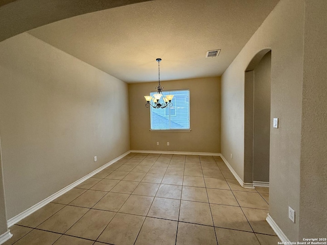 unfurnished dining area with a notable chandelier, light tile patterned floors, and a textured ceiling