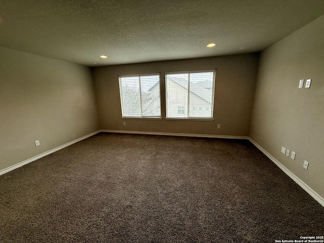 empty room with a textured ceiling and dark carpet