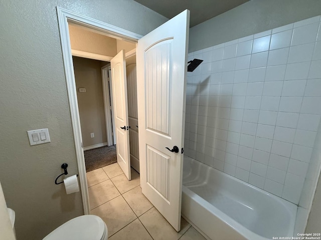 bathroom with tiled shower / bath, tile patterned floors, and toilet