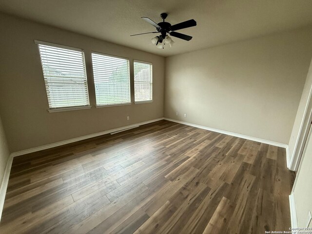 empty room with dark hardwood / wood-style floors and ceiling fan