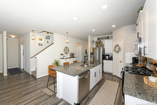 kitchen featuring white cabinetry, hanging light fixtures, an island with sink, and appliances with stainless steel finishes