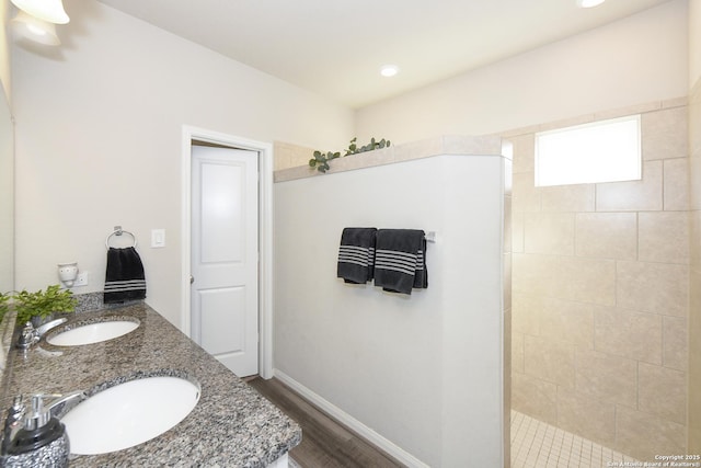 bathroom with hardwood / wood-style flooring, tiled shower, and vanity