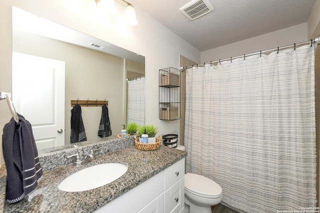 bathroom featuring vanity, a textured ceiling, and toilet