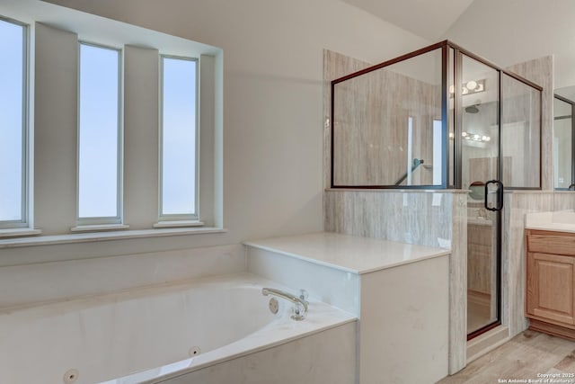 bathroom with plus walk in shower, wood-type flooring, vanity, and a healthy amount of sunlight