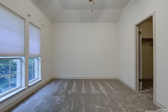 empty room with vaulted ceiling, carpet flooring, ceiling fan, and a healthy amount of sunlight