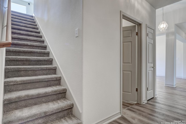 stairway featuring wood-type flooring and a chandelier