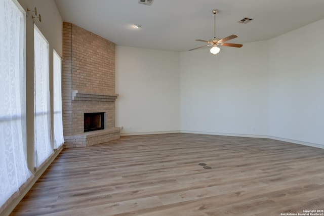 unfurnished living room with a brick fireplace, light hardwood / wood-style flooring, and ceiling fan