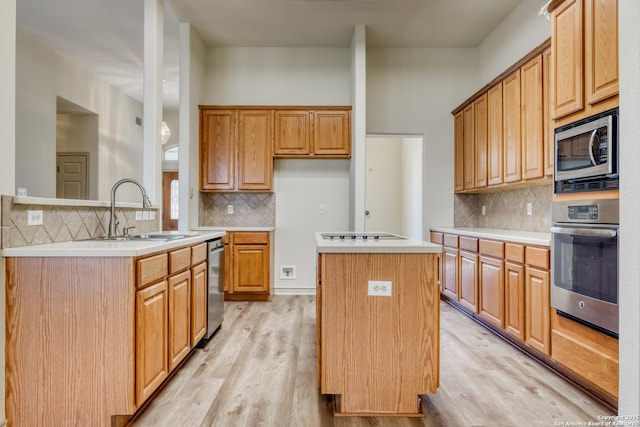 kitchen featuring sink, kitchen peninsula, a kitchen island, stainless steel appliances, and light hardwood / wood-style floors