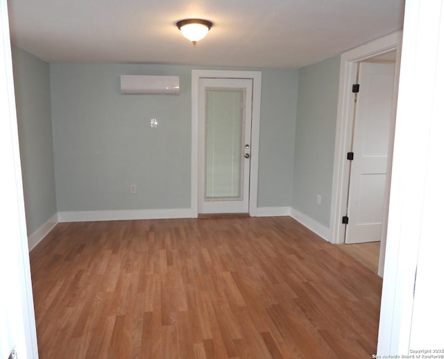 empty room featuring an AC wall unit and light wood-type flooring