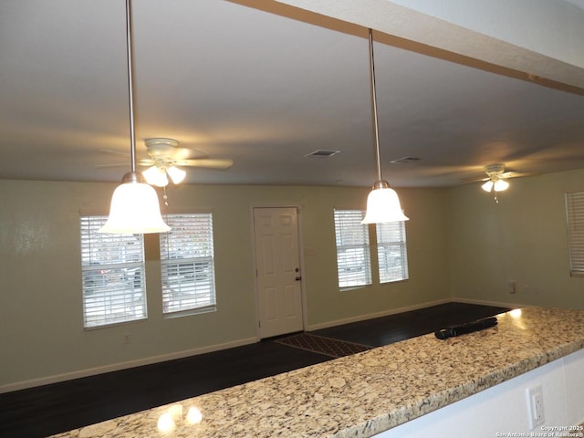 kitchen featuring ceiling fan, decorative light fixtures, and light stone countertops