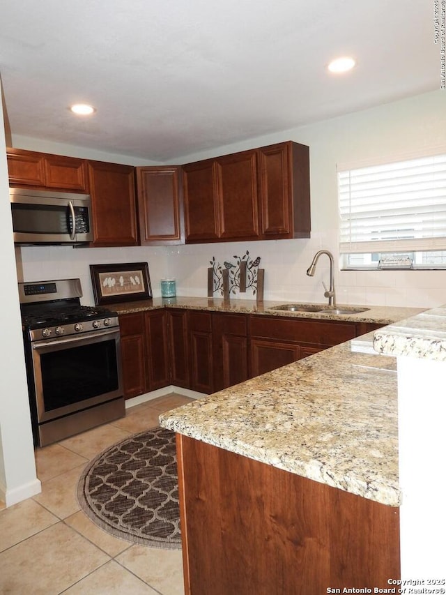 kitchen featuring light stone counters, sink, light tile patterned floors, and appliances with stainless steel finishes