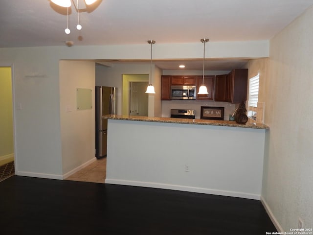 kitchen with stone counters, pendant lighting, light tile patterned floors, kitchen peninsula, and stainless steel appliances