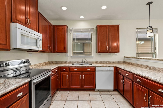 kitchen with sink, white appliances, decorative light fixtures, and light stone countertops