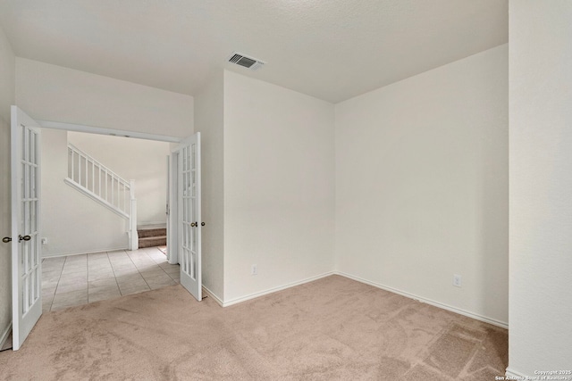 unfurnished room featuring light colored carpet and french doors