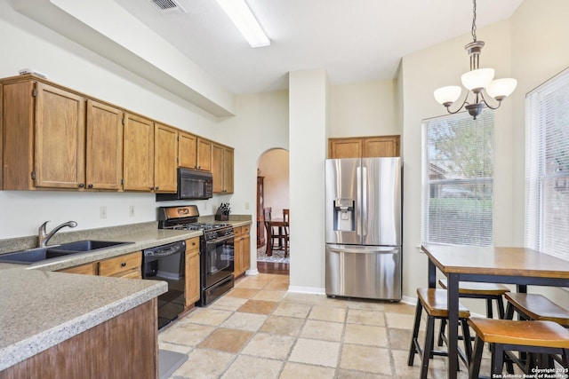 kitchen featuring sink, a chandelier, pendant lighting, a towering ceiling, and black appliances