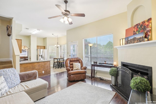 living room with ceiling fan with notable chandelier and dark wood-type flooring