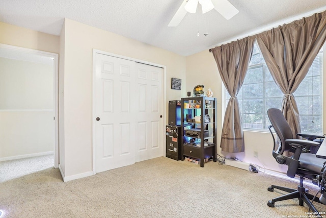 carpeted home office featuring ceiling fan and a textured ceiling