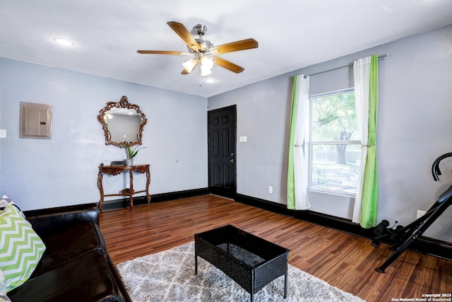 living room with wood-type flooring, electric panel, and ceiling fan