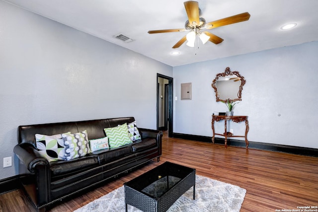 living room with ceiling fan, electric panel, and hardwood / wood-style floors