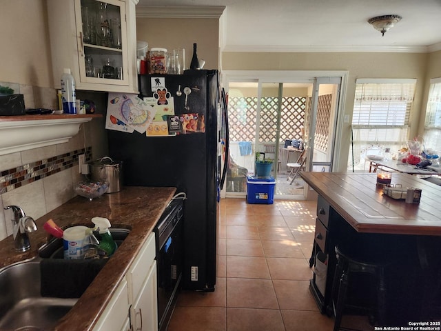 kitchen with light tile patterned flooring, sink, ornamental molding, white cabinets, and black appliances