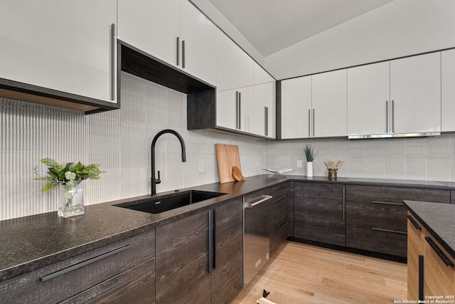 kitchen with tasteful backsplash, sink, light hardwood / wood-style flooring, and white cabinets