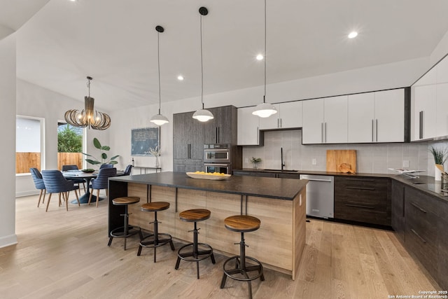 kitchen featuring sink, white cabinetry, stainless steel appliances, decorative backsplash, and decorative light fixtures