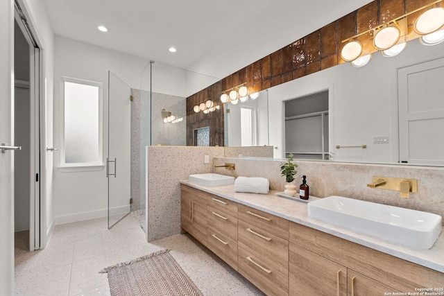 bathroom featuring vanity, a shower with shower door, and decorative backsplash