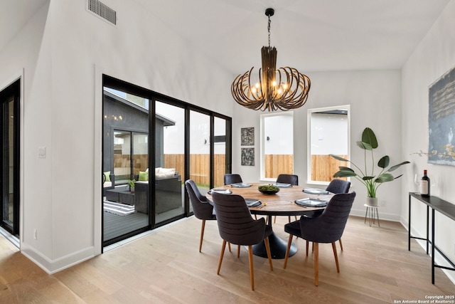 dining area featuring lofted ceiling, a chandelier, and light wood-type flooring