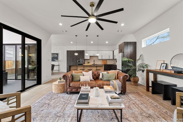 living room with lofted ceiling, sink, ceiling fan, and light wood-type flooring