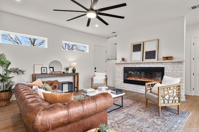 living room featuring hardwood / wood-style flooring, ceiling fan, and a brick fireplace