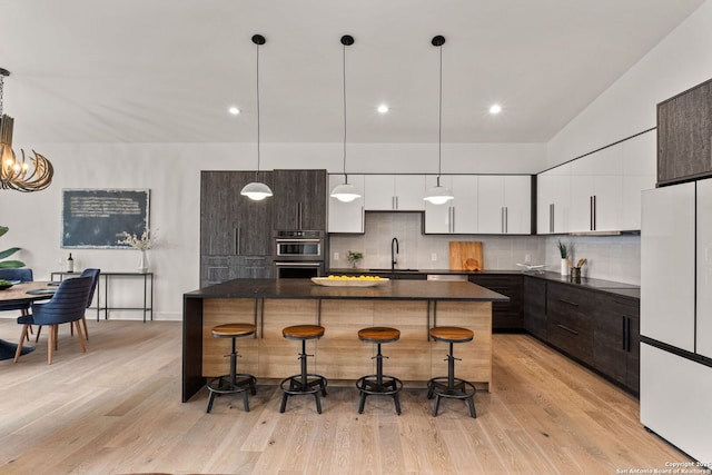 kitchen featuring white fridge, a kitchen bar, hanging light fixtures, and a kitchen island