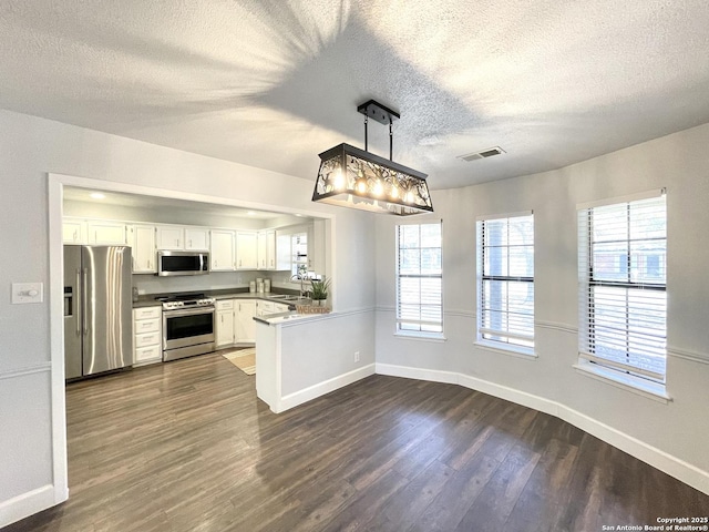 kitchen with sink, white cabinets, hanging light fixtures, kitchen peninsula, and stainless steel appliances