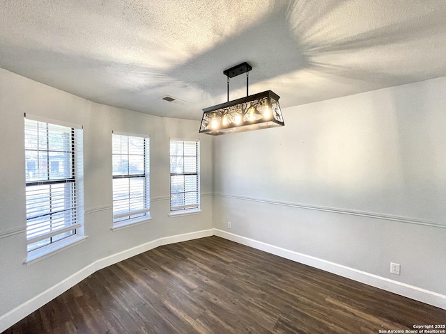 empty room with a textured ceiling and dark hardwood / wood-style flooring