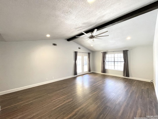 empty room featuring lofted ceiling with beams, dark hardwood / wood-style flooring, ceiling fan, a textured ceiling, and french doors