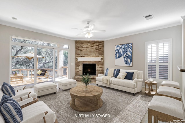 living room featuring crown molding, ceiling fan, and a brick fireplace