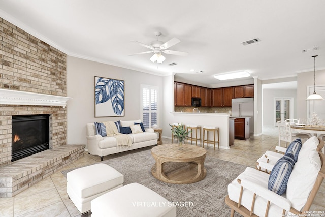 living room with crown molding, light tile patterned floors, ceiling fan, and a fireplace