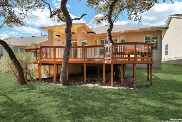 rear view of house with a deck, ceiling fan, and a lawn