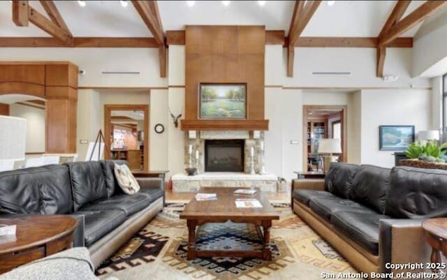 living room with beamed ceiling and a large fireplace