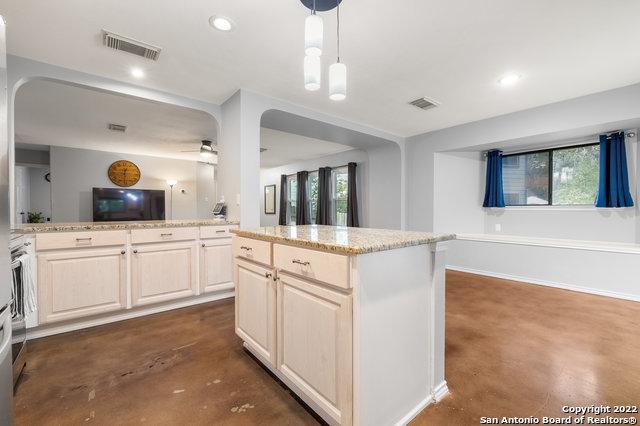 kitchen with pendant lighting, a wealth of natural light, light stone countertops, and a center island