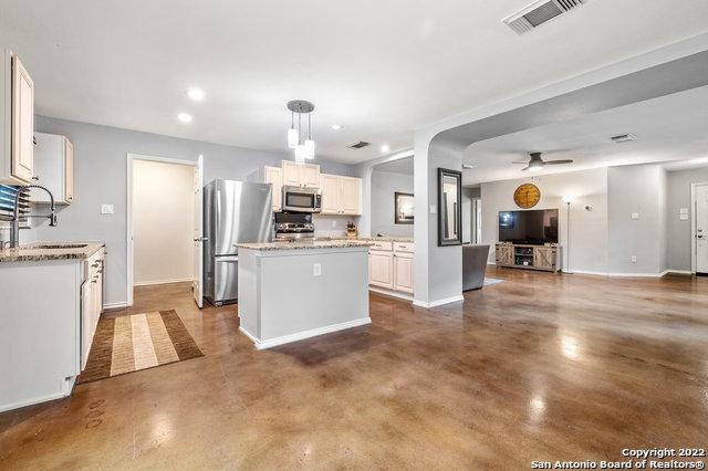 kitchen with pendant lighting, sink, stainless steel appliances, a center island, and white cabinets