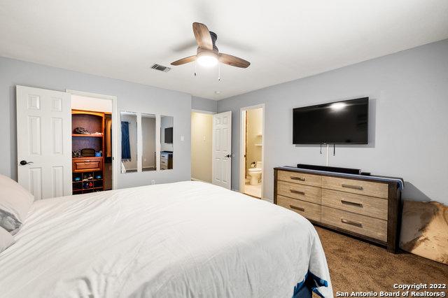 bedroom with ensuite bath, ceiling fan, and dark colored carpet