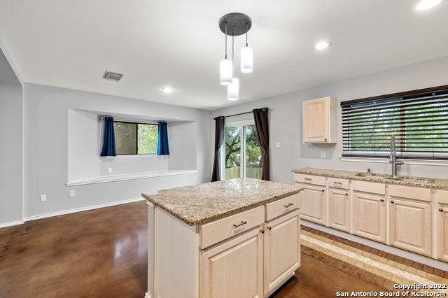 kitchen featuring sink, decorative light fixtures, light stone countertops, and a kitchen island