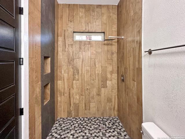 bathroom featuring tiled shower and toilet