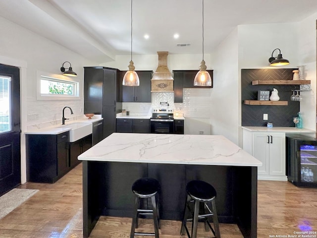 kitchen with sink, stainless steel appliances, light stone counters, decorative backsplash, and custom exhaust hood