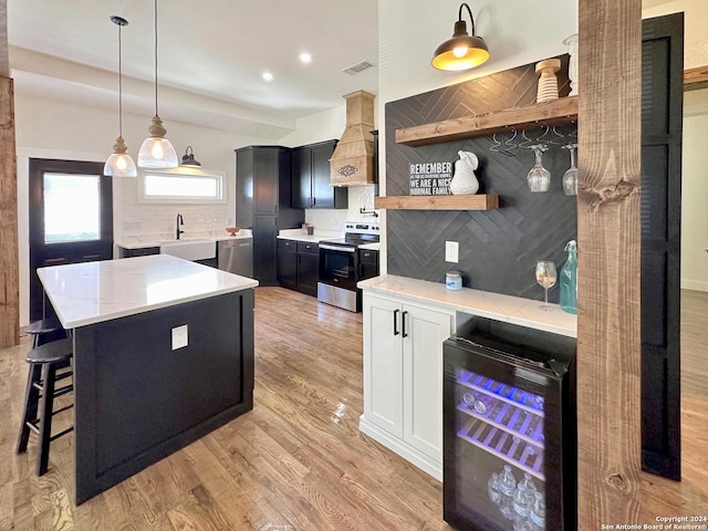 kitchen with wine cooler, appliances with stainless steel finishes, custom range hood, pendant lighting, and backsplash